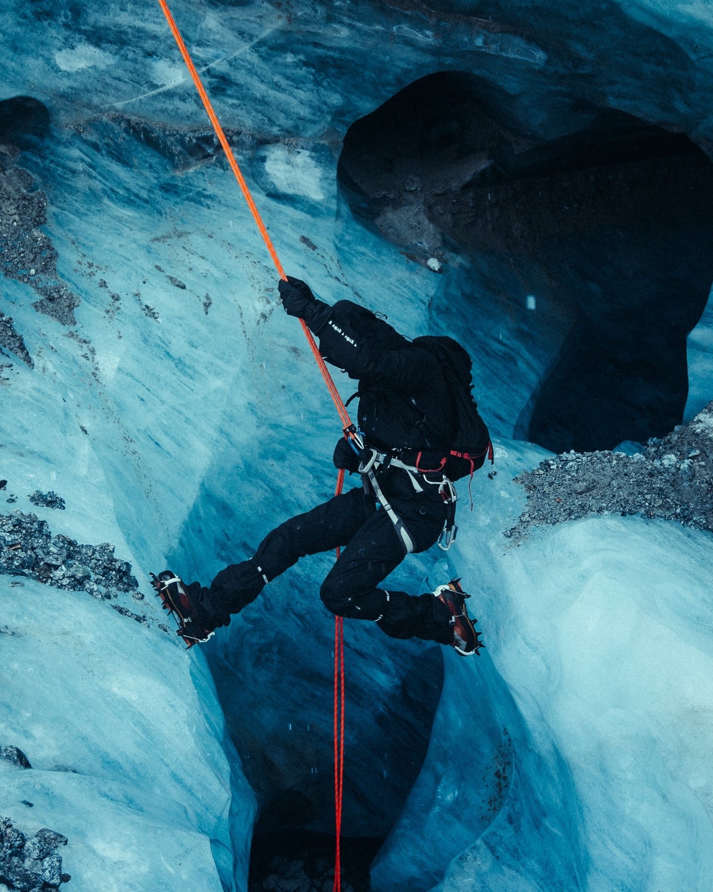 Climber abseiling in the black Manaslu Summit Shell alpine hardshell jacket inside a glacier crevasse